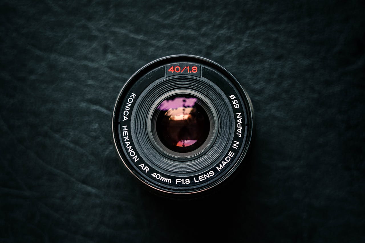 Top view of a vintage Konica Hexanon camera lens on a textured dark surface.